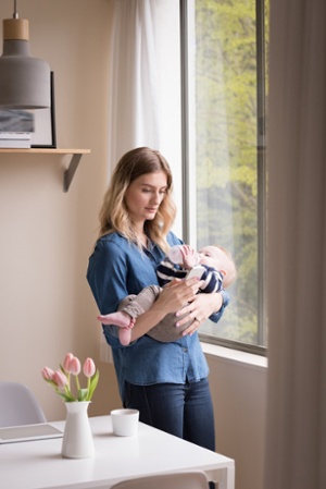 Young mother holding baby and looking at smartphone