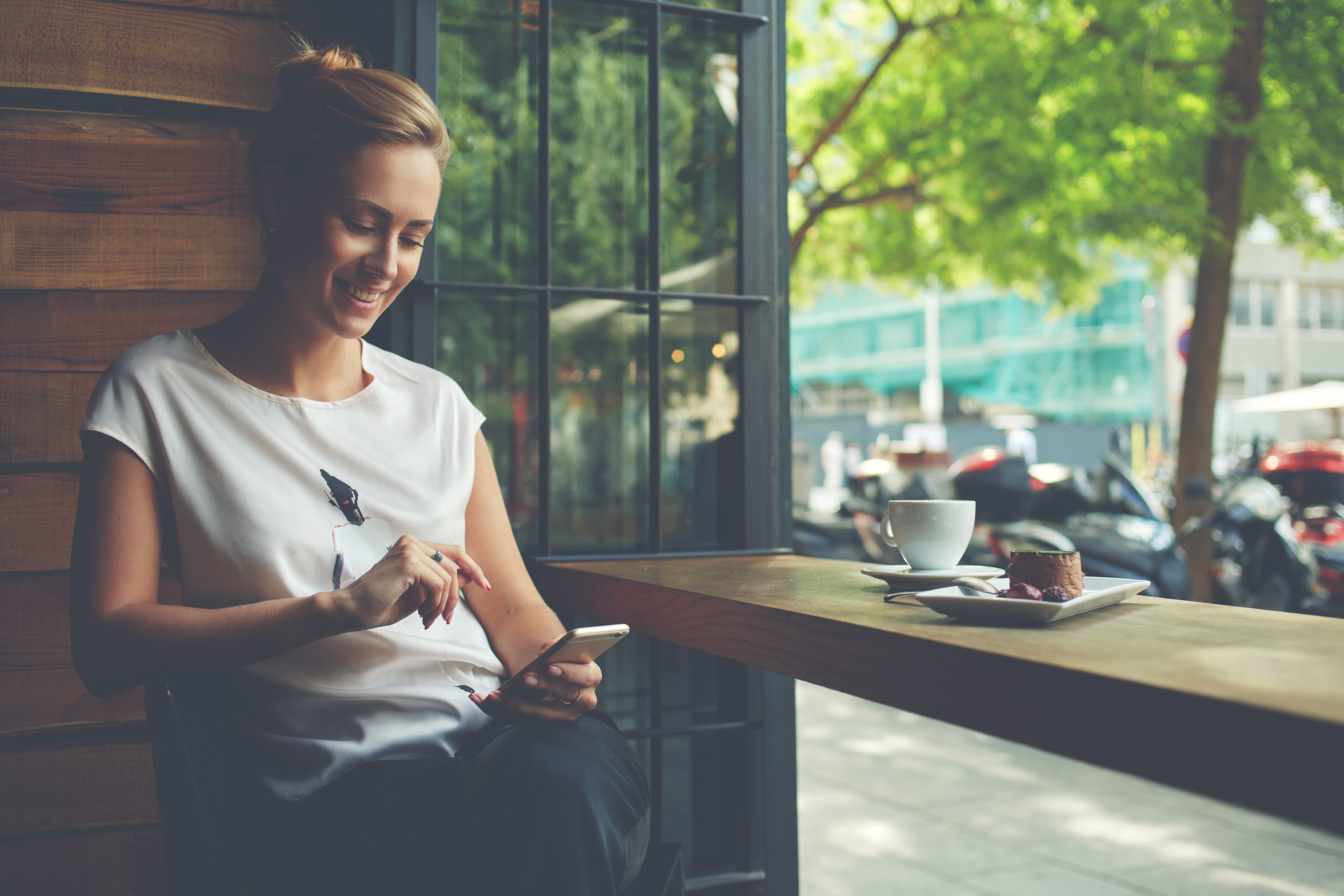 Young woman sitting in cafe looking at smartphone