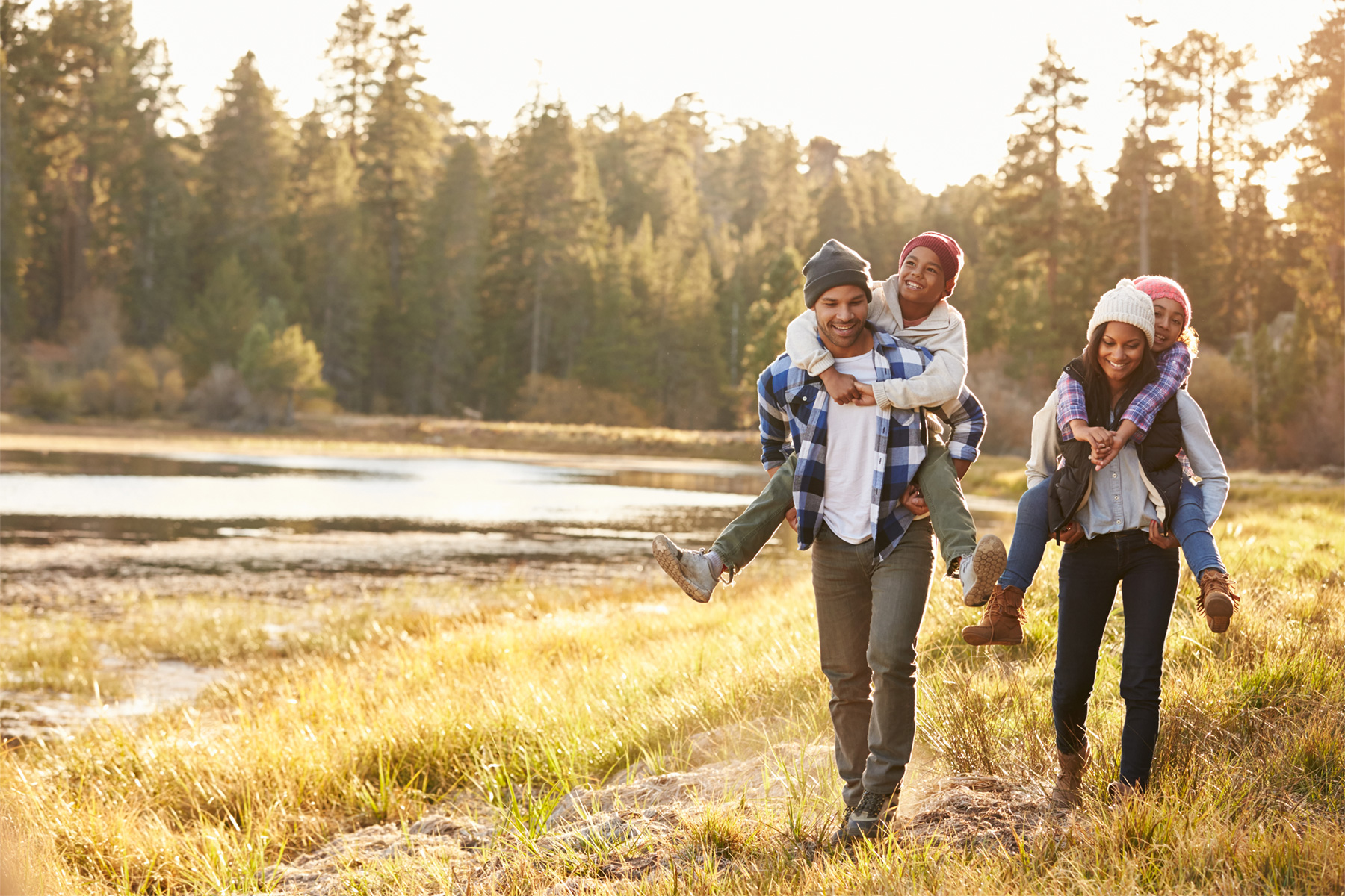 African American parents with older children on backs taking a walk in the woods