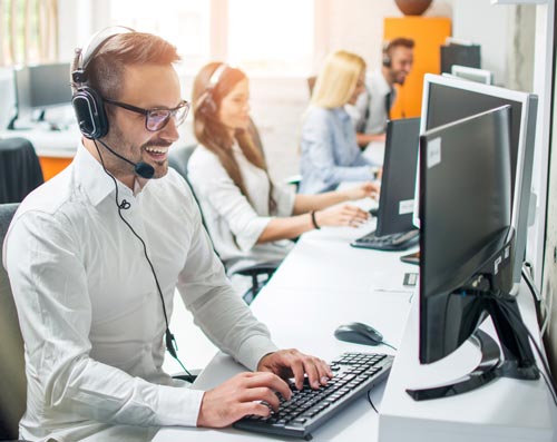 Happy male tech support employee with other employees in background