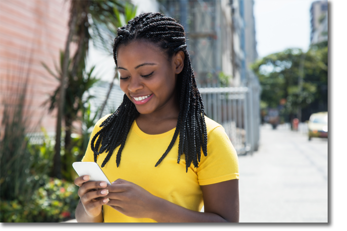 Young African American woman on street looking smartphone