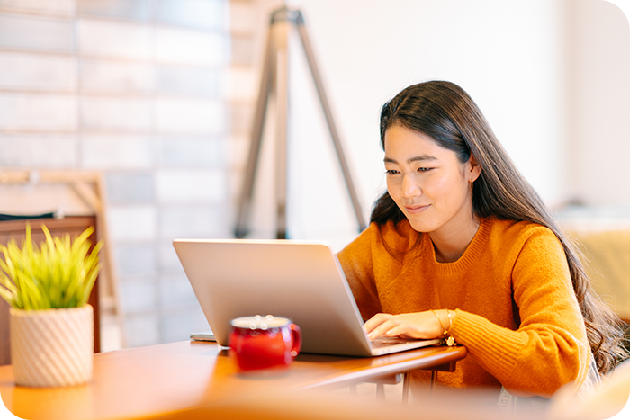 Asian young woman looking at laptop on desk