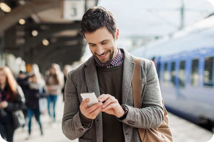 Man looking at smartphone with train and crowd in background