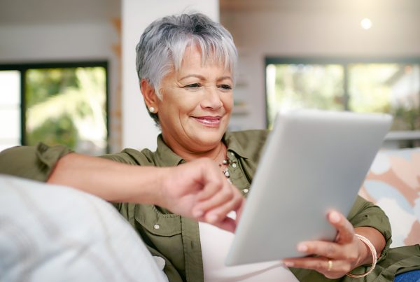 Happy older woman relaxing on the sofa with tablet