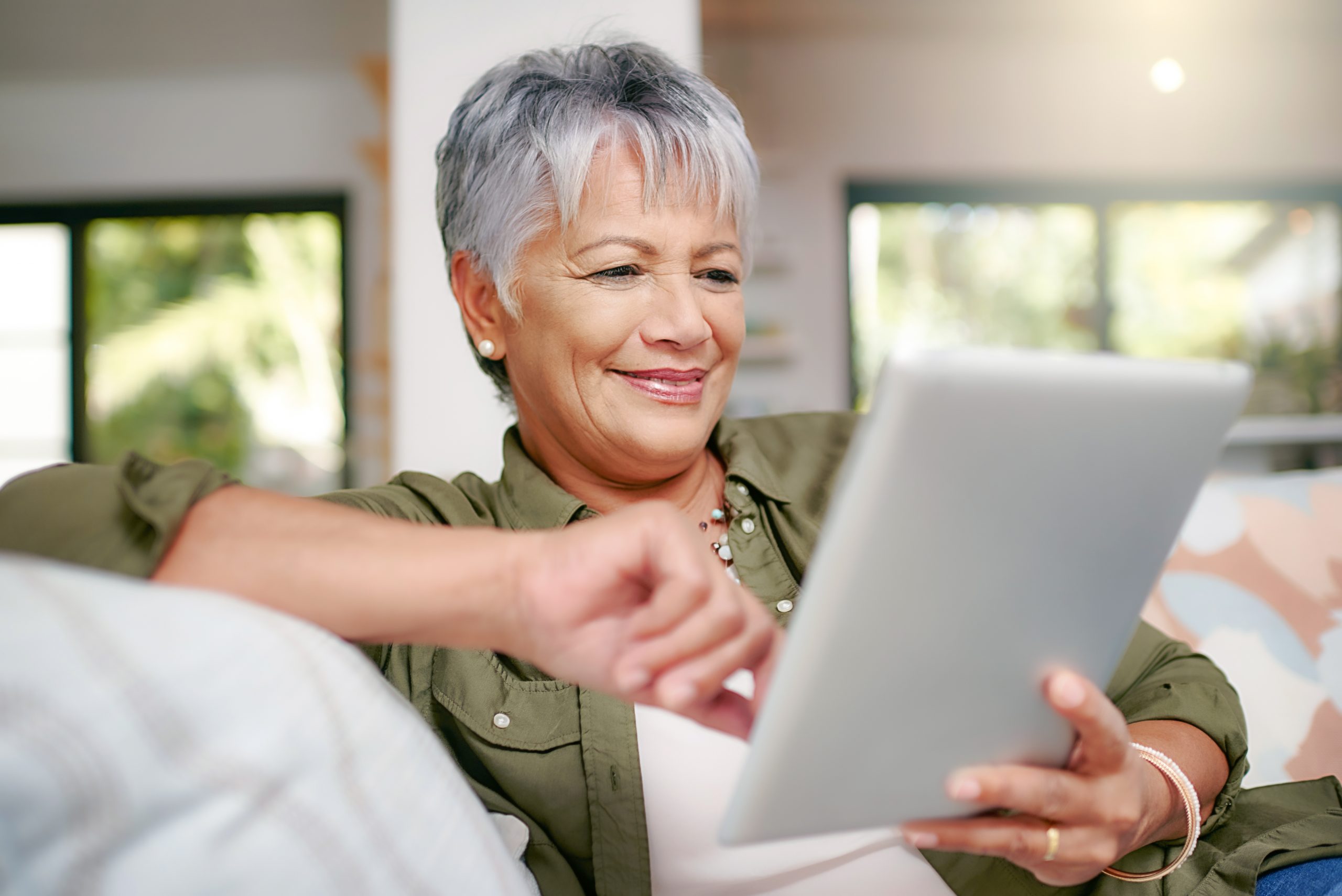 Happy older woman relaxing on the sofa with tablet