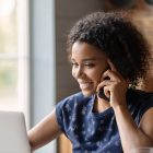 Biracial female hold cell at ear look at pc screen